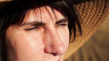 Female farmer in straw hat looking into wheat field and examining plantation at sunset. Close up face of adult beautiful woman illuminating by bright rays of sun. Concept of agriculture business video