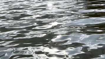 Scener surface of pond illuminated by sun at summertime. Calm view on sea with small waves at sunny day. Beautiful summer nature landscape. Concept of tranquility scene. Slow motion video