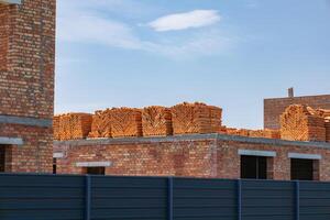 Workers are preparing for brick installation at a construction site where walls are being built with stacked bricks against a bright sky photo
