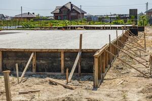 Workers are setting up a concrete foundation for a residential project in a growing suburban neighborhood under clear skies photo