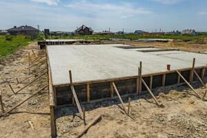 Workers set up a solid foundation for a building in a quiet countryside location as construction progresses under a sunny sky photo