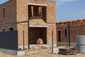 New brick buildings are under construction with sand piles and building materials scattered around the site during bright daylight photo
