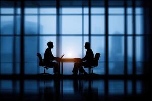 Two business people sitting at a table in front of a large window photo