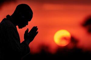 A man praying in front of the sun photo