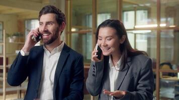 Cheerful multiethnic business coworkers man woman talking mobile phone call laugh at office happy smiling Korean businesswoman Caucasian businessman managers speaking cellphone chat deal negotiation video