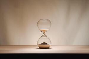 A simple hourglass on a wooden table with a beige backdrop, symbolizing time flow and minimalistic living. Running out of time, uncluttered presentation for stylish concepts. photo