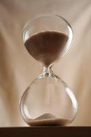 Minimalist Glass full time Hourglass on Wooden Surface with Beige Background hero shot low-key photo