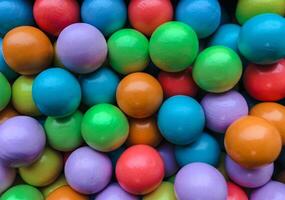 A vibrant and colorful overhead shot of numerous wooden or painted balls, tightly packed together, creating a lively full-frame texture. photo