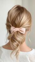 Blonde woman from behind displaying intricate formal hairstyle with soft braided bow, highlighting elegant styling for pink events photo