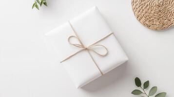Minimalist white gift box decorated with a green sprig and tied with twine, conveying simplicity and elegance on white a background photo