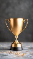 Shiny gold trophy with confetti on a gray background, celebrating achievement and success in competition photo