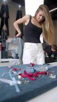 A young woman is trying on a denim skirt in a craft store, which is decorated with feathers. vertical video