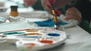 A close-up of a paintbrush being dipped into a paint palette to decorate jeans and create a unique, one-of-a-kind design. video