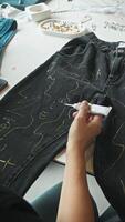 During the workshop, a woman transformed her old jeans by drawing a portrait on them, giving them new life. Vertical. video