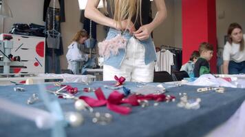 A young, slim woman is trying on a skirt that she created during a masterclass on crafting and decorating denim clothing. video