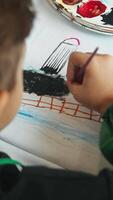 The boy is trained in drawing on fabric, creating designs on clothes using paint. Vertical. High angle. video