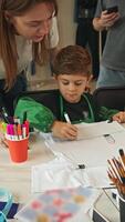 A young student creates a unique design for his T-shirt with the help of a supportive and caring art teacher. video