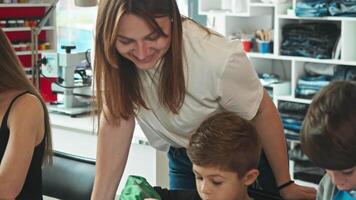 Young mother watches with great pleasure and emotion as her sons express themselves creatively, decorating and making craft clothes with paints and markers. video