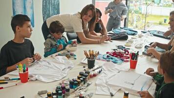 Group of parents, together with their children, create unique craft items of clothing. They decorate them and create beautiful drawings. video