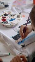 A child enthusiastically paints a T-shirt during an art class. Vertical. video
