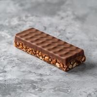 Delicious Chocolate Covered Nut and Cereal Bar on Gray Textured Background. A close-up studio shot of a single energy bar. photo