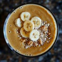 Delicious Banana Peanut Butter Smoothie with Granola Topping. A close-up overhead shot of a creamy smoothie garnished with banana slices and granola. photo