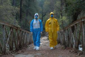 Two people wearing protective clothing walk across a bridge photo
