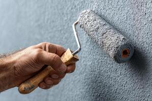 A man is painting a wall with a roller photo