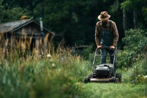 A man in overalls mowing grass with a lawn mower photo