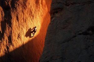 A climber is climbing up a rock face photo