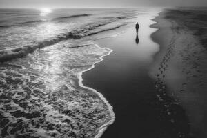 A black and white photo of a person walking along the beach