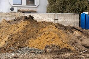 Construction workers are preparing a site with large mounds of dirt and gravel to begin new residential building projects in the neighborhood photo