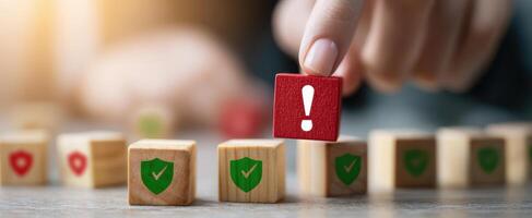 The hand selecting a warning block among green shield icons on a table. photo