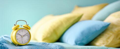 The cheerful yellow alarm clock nestled among colorful pillows in a cozy setting. photo