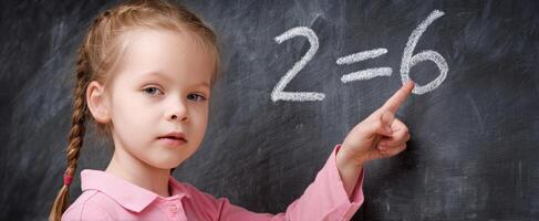 The young girl solving a mathematical equation on a classroom chalkboard. photo