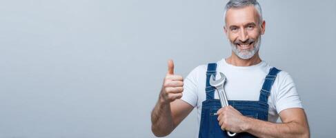 The cheerful handyman giving a thumbs-up while holding a wrench. photo