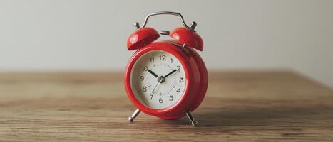 The vibrant red alarm clock on a rustic wooden desk. photo