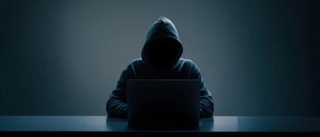 The mysterious hacker working on a laptop in a dark environment. photo