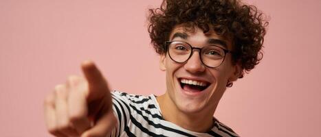 The joyful young man pointing enthusiastically against a pink background. photo