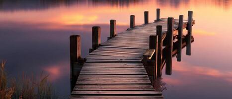 The peaceful wooden dock stretching over calm reflective waters at sunset. photo