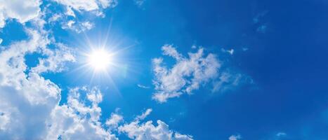 The beautiful sun shining through fluffy clouds in a vibrant blue sky. photo