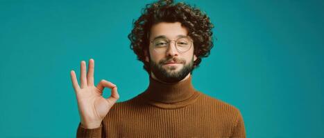 The man making an okay gesture with a confident smile against a turquoise background. photo