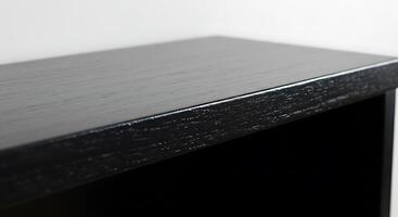 A black shelf with a white wall behind it photo