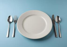 Empty plate, fork, knife and spoon on blue background photo