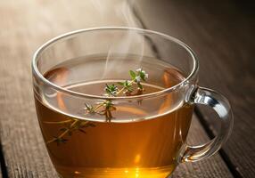 A cup of tea with herbs on top of a wooden table photo