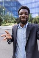 Young successful businessman uses phone for call, man looks into smartphone camera. View of webcam of call application. photo