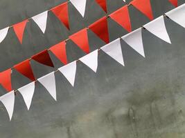 Red and white triangular bunting flags hang against a gray background, creating a festive and cheerful atmosphere. photo