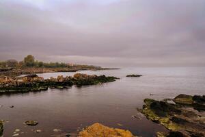 a body of water with rocks and a sky photo