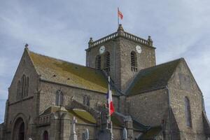 A large church with a clock tower in barfleur photo