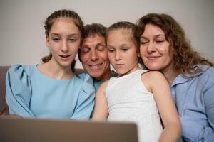 Family Laptop Screen. Two daughters watch screen with parents at home in daytime. photo